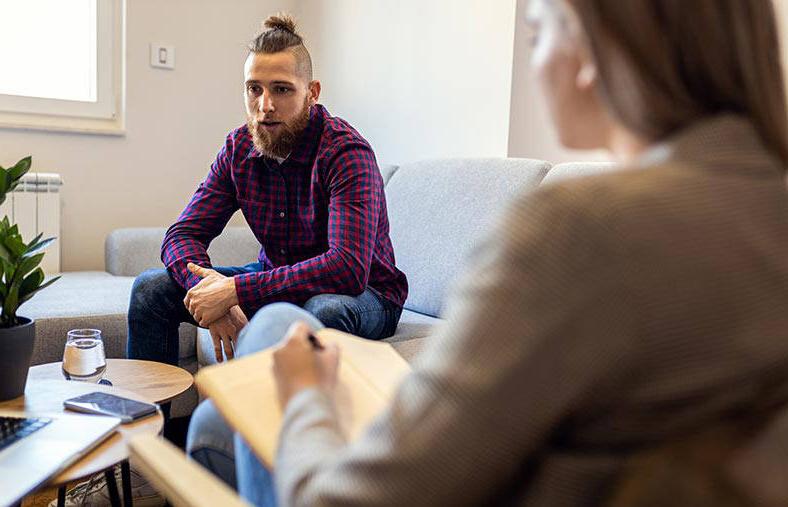 Young man talking to female psychologist during a session